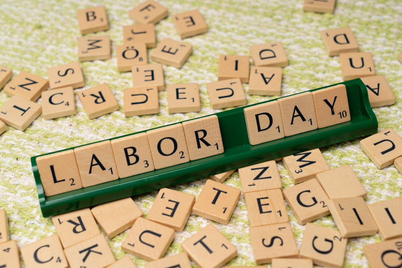 Scrabble tiles forming the phrase Labor Day on a green surface, symbolizing the holiday.
